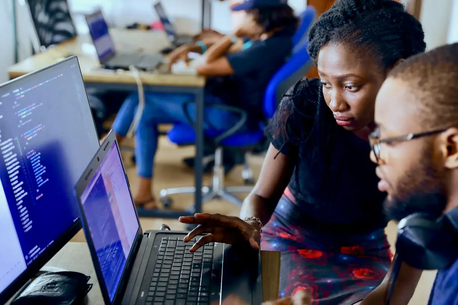 Two young colleagues look at a laptop together in a shared office